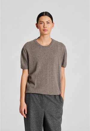 Brun kortærmet strikket sweater med rund halsudskæring, blød tekstur og afslappet pasform, parret med mørkegrå skræddersyede bukser.