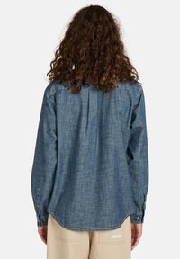 Denim shirt in een medium blauwe tint, met lange mouwen, knoopmanchetten, een plooi aan de achterkant en een afgeronde zoom. Gladde textuur met een casual ontwerp.