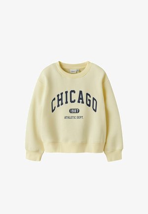 Sweat-shirt jaune clair avec le texte « CHICAGO 1987 ATHLETIC DEPT. » imprimé en bleu foncé sur le devant, avec poignets côtes et col rond.