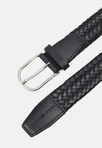 Cintura in pelle tessuta nera con una fibbia rettangolare in argento e un'estremità in pelle liscia con il nome del marchio in rilievo. Design testurizzato su tutta la superficie.