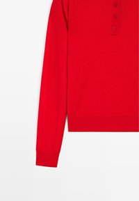 Polo rossa a maniche lunghe con abbottonatura a tre bottoni, polsini e orlo a costine. Tessuto morbido e design a taglio dritto.