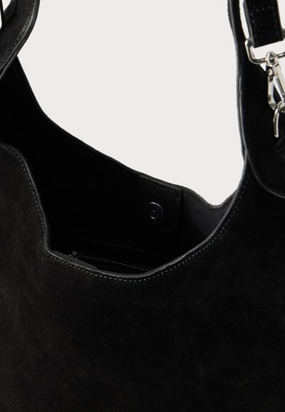 Μαύρη σουέντ τσάντα ώμου με μαγνητικό κούμπωμα, ασημί μεταλλικά εξαρτήματα και εσωτερική τσέπη με φερμουάρ ορατή στην επάνω άνοιξη.