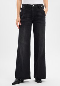 Czarne szerokie spodnie dżinsowe z wysokim stanem, wykonane z denimu. Posiadają przednie kieszenie, zapięcie na guzik oraz delikatne przetarcia na materiale.