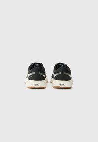 Svart sneakers med teksturert overdel, med hvite detaljer, en polstret såle og en såle laget av gummigummi. Logo synlig på hælen.