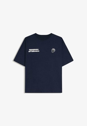 T-shirt bleu marine à manches courtes avec le texte « season of bloom » et un petit dessin de fraise blanche sur la poitrine.