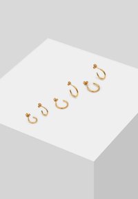 Orecchini a cerchio in oro di varie dimensioni, con semplici design curvi. Due paia includono accenti floreali, mentre gli altri sono lisci e privi di decorazioni.