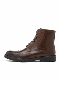 Brązowe skórzane botki z zaokrąglonym noskiem, sznurowane, z ozdobnymi przeszyciami typu brogue. Posiadają solidną, gumową podeszwę z bieżnikiem oraz wyściełany kołnierz.