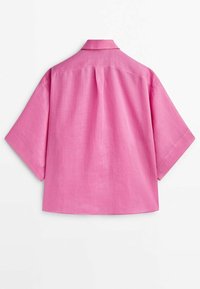 Chemise à manches courtes avec col, en tissu uni rose vif. Présente un pli au dos et une forme ample et carrée. Texture légère.