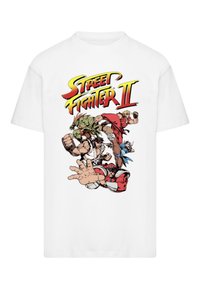 Hvid bomulds T-shirt med en farverig grafisk tryk af figurer fra "Street Fighter II" i actionposer, med fed skrift ovenfor.