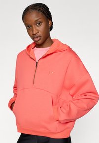 Κοραλί φούτερ με φερμουάρ στο γιακά, άνετη εφαρμογή, τσέπη καγκουρό και ριμπ μανσέτες. Το ύφασμα είναι λείο και υφασμένο, με μικρό λογότυπο.