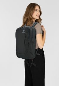 Schwarzer Rucksack mit einem schlanken Design, aus strapazierfähigem Stoff gefertigt. Verfügt über gepolsterte Träger, mehrere Fächer und ein Logo auf der Vorderseite.