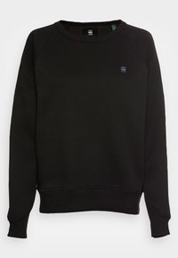 Felpa nera realizzata in tessuto strutturato, con collo a giro e polsini a costine, e un piccolo logo sul petto. Design semplice e classico.