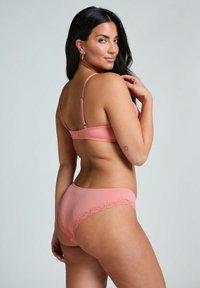 Rosa gerippter BH und passender Slip mit Spitzenbesatz. Der BH verfügt über verstellbare Träger und einen Hakenverschluss auf der Rückseite. Glatte Stofftextur.