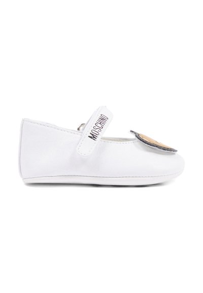 Chaussure bébé Mary Jane blanche avec un patch visage sur l'orteil et une bride portant l'inscription "MOSCHINO" sur le dessus.