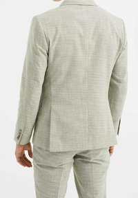 Ljusgrön rutig kavaj, strukturerad tyg, enkel slits, knappdetaljer på ärmarna, skräddarsydd passform, matchande byxor synliga.