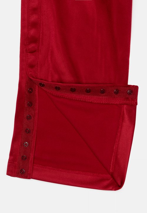 Punane kangas sileda tekstuuriga, millel on külg volditud õmblus, mille serva kaunistavad kuus ümmargust tumedat nööpi.