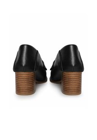 Zapatos de cuero negros de corte bajo, con parte trasera redondeada y tacones de madera apilados que presentan un diseño texturizado.