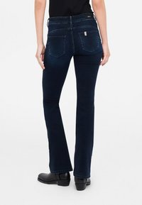 Jeans in denim bootcut blu scuro con un classico design a cinque tasche. Presentano una vita media e dettagli di cucitura sottili sulle tasche posteriori.