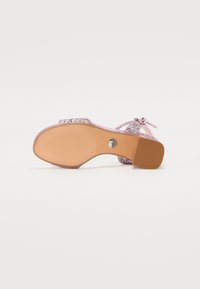Rožinė blizgi slingback tipo batai, pasižymintys žemu, stačiakampiu kulnu ir tekstūruota gumaota padais su metaliniu logotipo emblem.