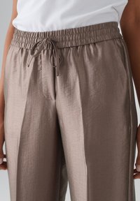 Lichtbruine, lichte broeken met een elastische tailleband en een trekkoord, met een gladde textuur en een losse pasvorm.
