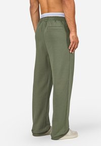 Πράσινες φόρμες με χαλαρή εφαρμογή, ελαστική μέση με λευκές λεπτομέρειες και πίσω τσέπη. Κατασκευασμένες από μαλακό, υφασμάτινο ύφασμα.