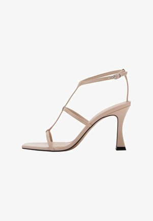 Beige højhælede sandaler med en slank ankelrem, minimalistisk design, spidse tå og en kontrastfarvet sort detalje på hælen.