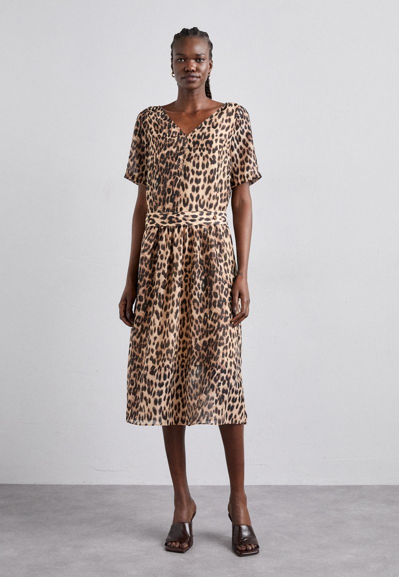 Robe midi imprimée léopard en tissu léger avec des manches courtes, un col en V et une taille ceinturée, dotée d'une jupe fluide. Accents marron dans les chaussures.