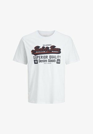 T-shirt en coton blanc avec texte imprimé en noir et rouge, assortie à un jean en denim bleu clair et des baskets blanches. Design simple, coupe décontractée.