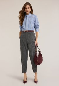 Blau-weiß gestreiftes Hemd, graue Cordhosen mit umgeschlagenen Bündchen, bordeauxroter Gürtel, passende Handtasche und bordeauxrote High Heels.