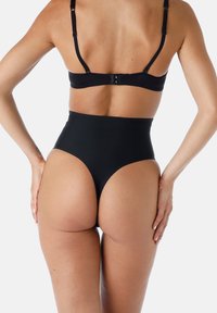 Slip nero a vita alta con una texture liscia, design senza cuciture e un taglio moderato alle aperture delle gambe. Spalline regolabili sul reggiseno.