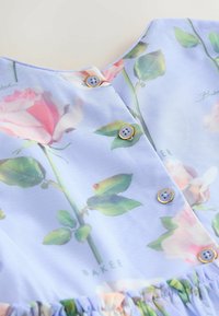 Helles blaues Blumenkleid mit Rosenmuster, goldenen und blauen Knöpfen sowie einem gerafften Saum. Weicher, transparenter Stoff.