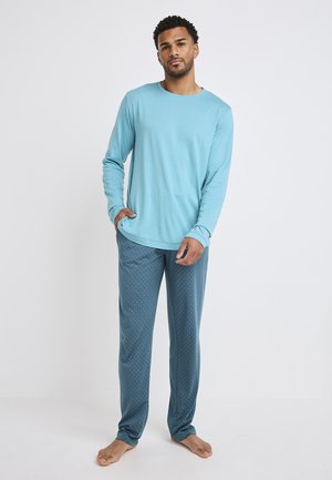 Light blue long-sleeve shirt paired with dark blue pajama pants featuring a white polka dot pattern. Soft fabric, relaxed fit.