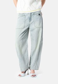 Lyseblå, høy midje jeans med en avslappet passform, med baklommer og subtil falming. Kombinert med lyse blokkhelte sandaler.