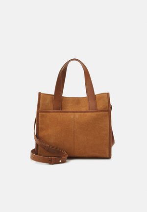 Bruine suede totebag met bruine leren handvatten en een verstelbare schouderband. Heeft een rechthoekige vorm en twee verticale naden aan de voorkant.