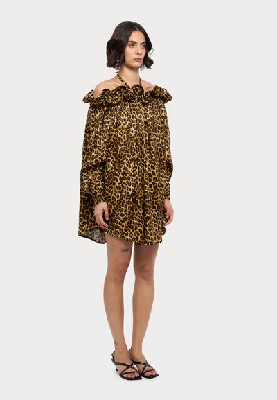 Vestido de leopardo con escote Bardot, cuello con volantes, mangas largas y corte holgado. Combinado con sandalias negras de tiras.
