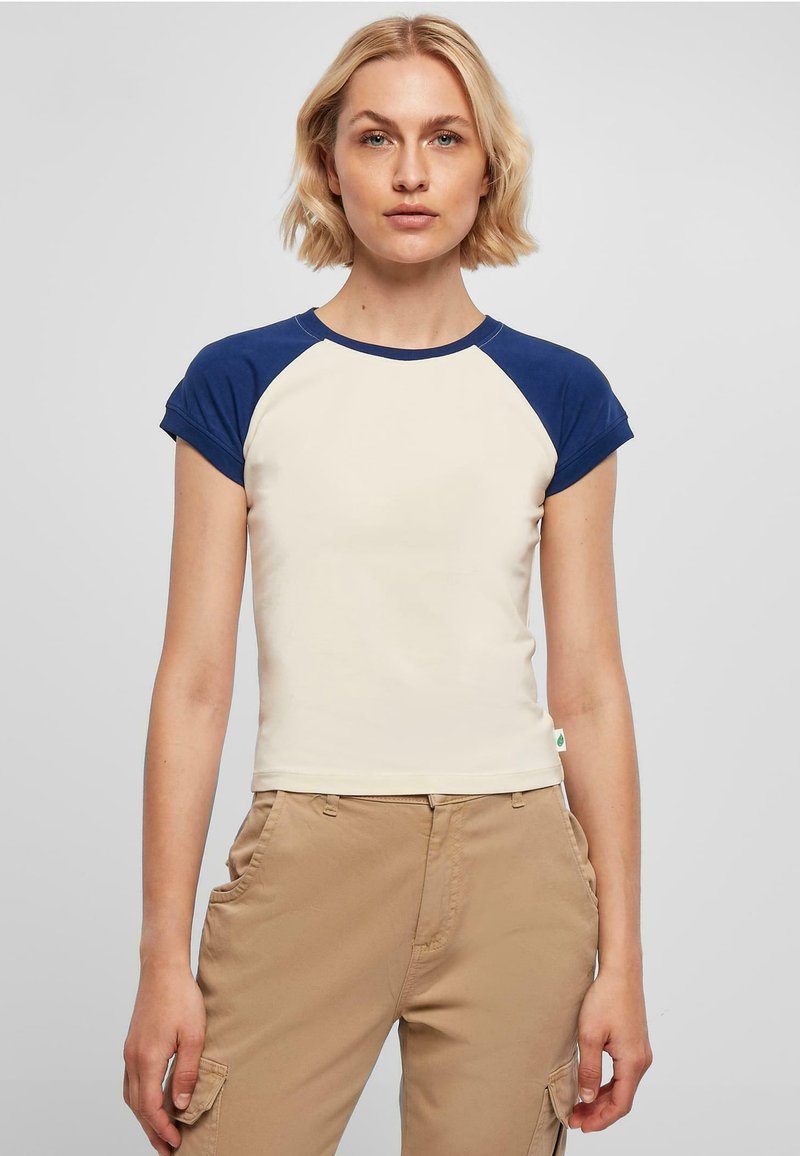 T-skjorte med korte ermer i kremfarge med marineblå raglan-ermer. Laget av myk stoff, har en tettsittende design og rund hals.