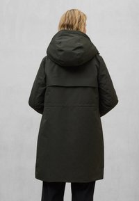 Tmavě zelený parka kabát s kapucí a volnějším střihem, vybavený plochým sedlem, dlouhými rukávy a středně dlouhým lemem. Hladká textura.