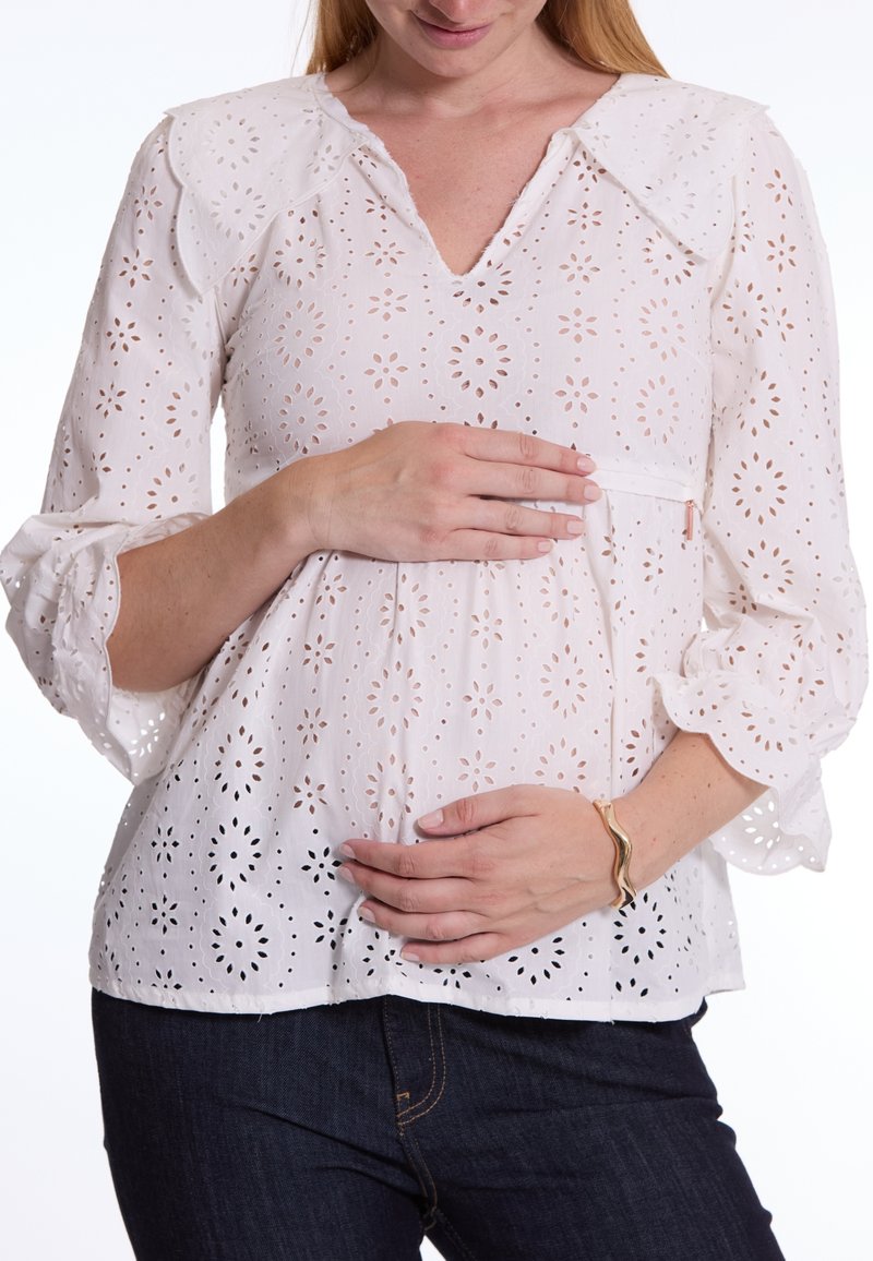 Witte katoenen blouse met oogjesontwerp en bloempatronen, V-hals, kraag en klokmouwen, gedragen over donkerdenim broek.