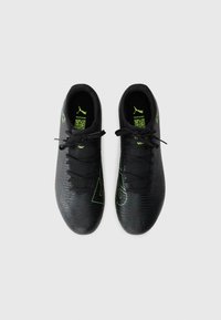 Botas de fútbol negras con superficie texturizada, con detalles y logo en verde neón. Los cordones son negros, con un diseño estampado en la parte superior.