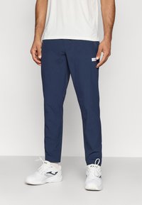 Ναυτικές αθλητικές παντελόνες με στενή εφαρμογή, φτιαγμένες από ελαφρύ ύφασμα, με μικρή ετικέτα λογότυπου στο πλάι και λεία υφή.