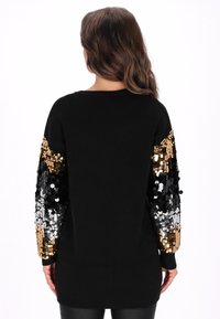 Pulover negru cu mâneci lungi împodobit cu paiete aurii, argintii și negre, cu guler rotund și tiv inferior reiat.