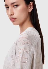 Maglione a maglia grigia chiara con un motivo aperto e testurizzato e un ampio scollo; presenta una vestibilità comoda e spalle leggermente scese.