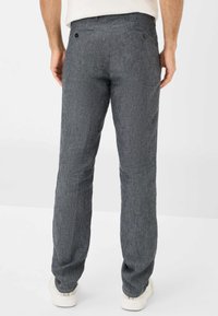 Pantaloni in lino grigi con finitura testurizzata, taglio dritto, tasche posteriori e dettagli in bottoni. Abbinati a semplici sneakers bianche.