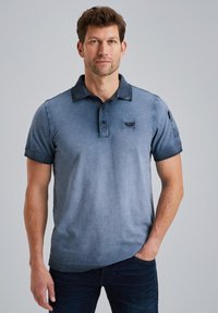 Polo a maniche corte in tessuto blu sfumato, con colletto, patta con tre bottoni e una piccola patch con logo sul petto.