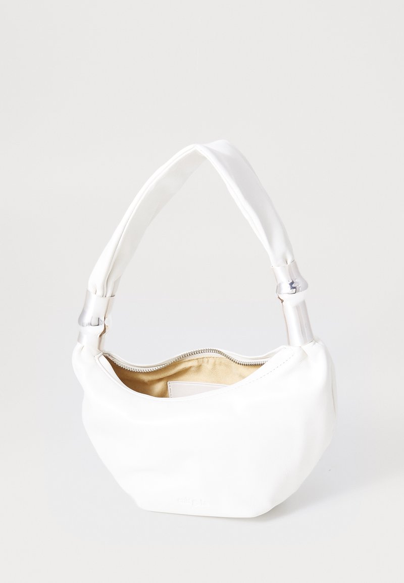 White leather handbag with padded handle and silver metal accents, open top zipper revealing beige interior lining and an inner pocket.