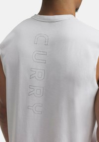 White sleeveless shirt featuring the word "CURRY" in embossed text down the back, made from a soft, smooth fabric.