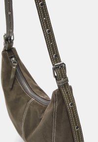 Green suede handbag with silver hardware, featuring white stitching, a zip closure, and an adjustable strap with decorative rivets.