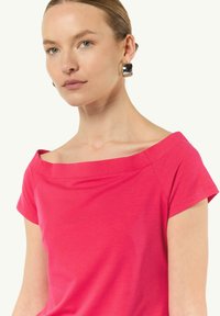 Dopasowana różowa koszulka z dekoltem typu off-the-shoulder i krótkimi rękawami, wykonana z miękkiej, gładkiej bawełny.