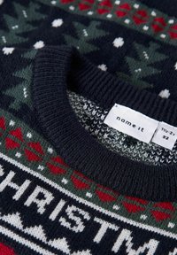 Maglione lavorato a maglia di colore blu navy con motivi festivi; presenta alberi, cuori e punti bianchi. Collo a coste; etichetta visibile con dettagli sulla taglia.
