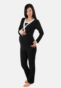 Conjunto de loungewear de maternidad negro que incluye una blusa de manga larga con escote en V y detalles de encaje, y pantalones negros a juego, todo fabricado con un tejido suave.